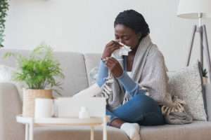 Sick woman taking her temperature and blowing her nose