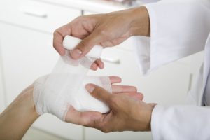 Doctor applying a dressing for a wound on a hand